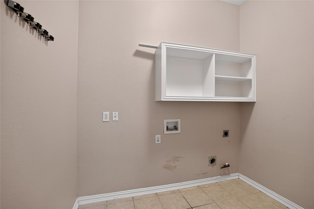 111 Ripplewood Coppell, TX 75019 - Photo 16 of 34 Utility room featuring tile flooring, a built-in wall cabinet with shelving, and appliance hookups