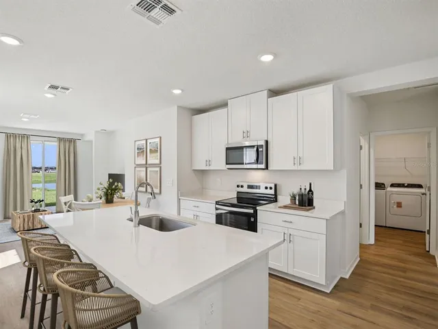 a kitchen with stainless steel appliances kitchen island granite countertop a sink a stove a refrigerator cabinets and chairs