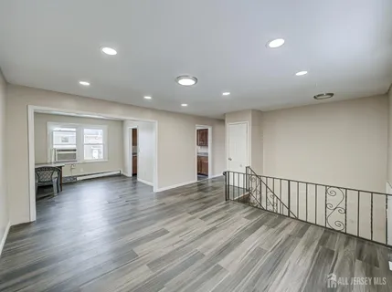 a view of an empty room with wooden floor and windows