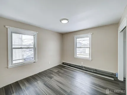 a view of an empty room with wooden floor and closet