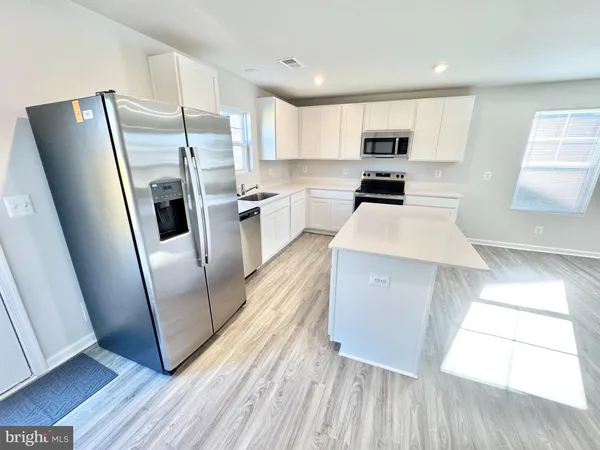 a kitchen with stainless steel appliances a refrigerator a sink a stove a microwave and cabinets