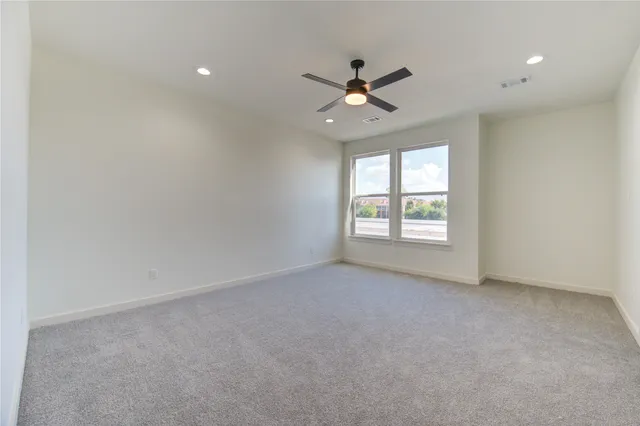 an empty room with a window and a fan