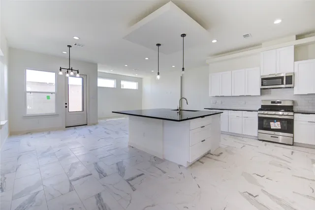 a kitchen with stainless steel appliances granite countertop a stove a sink and a refrigerator