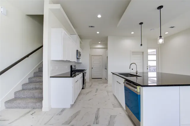 a view of kitchen with refrigerator and white cabinets