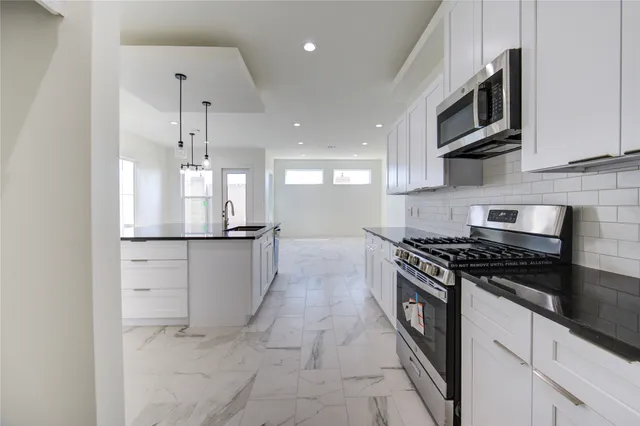 a kitchen with stainless steel appliances granite countertop a stove a refrigerator and a microwave