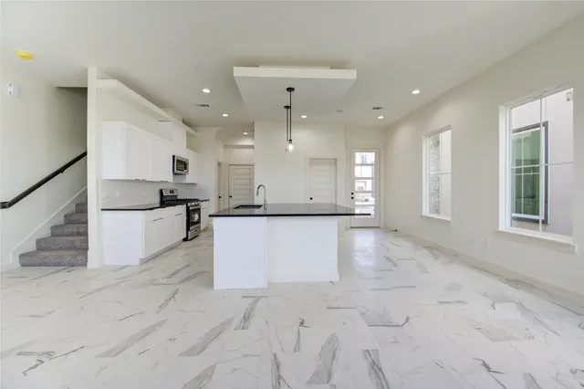a view of kitchen with refrigerator and white cabinets