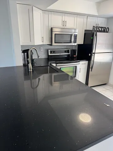 a kitchen with stainless steel appliances a stove a refrigerator a microwave a sink and cabinets