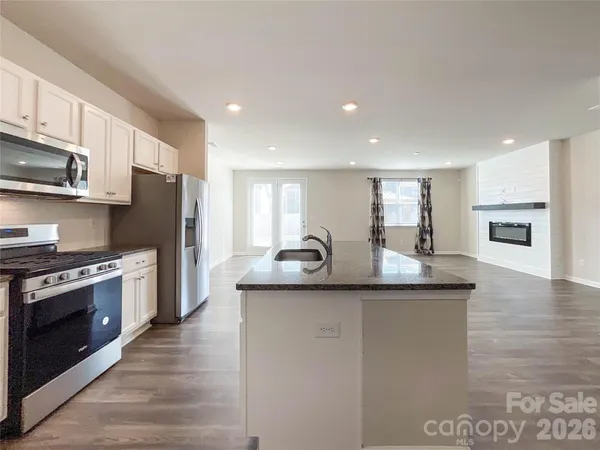 a kitchen with stainless steel appliances granite countertop a sink stove microwave and refrigerator