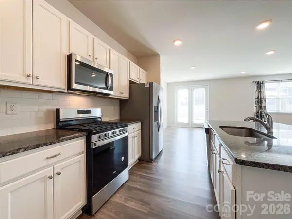 a kitchen with stainless steel appliances granite countertop a sink and a refrigerator