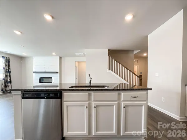 a kitchen with stainless steel appliances granite countertop a refrigerator a stove top oven a sink and dishwasher with wooden floor