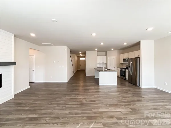 a view of an empty room with wooden floor and a fireplace