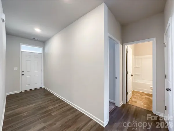 a view of hallway with a room and wooden floor