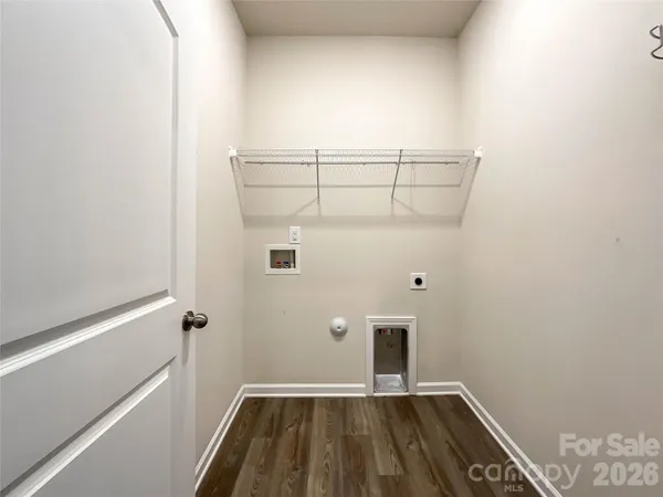 a kitchen with stainless steel appliances a microwave a stove a sink dishwasher a refrigerator and white cabinets with wooden floor