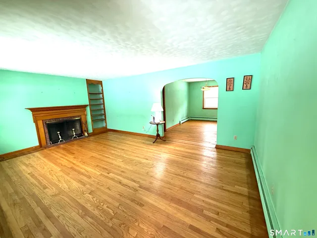 a view of a livingroom with wooden floor and a fireplace