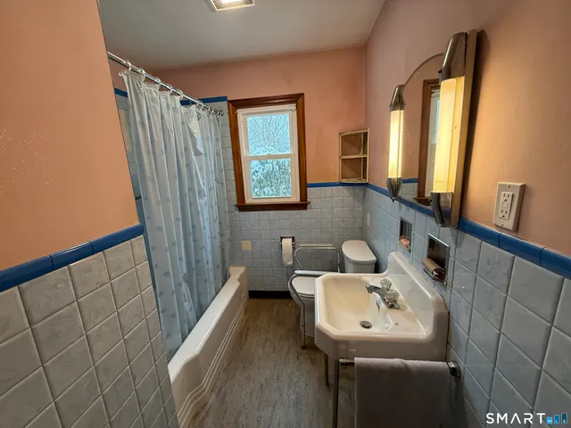a bathroom with a sink a mirror a toilet and a window