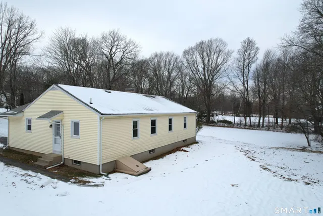 a view of a white house with a yard covered in snow
