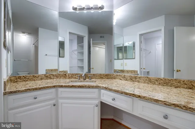 a bathroom with a granite countertop sink and a mirror