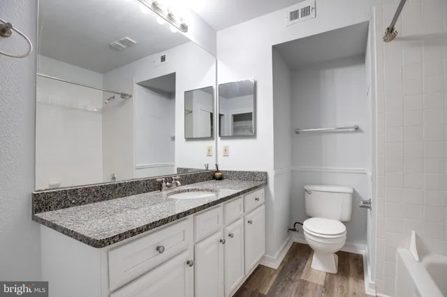 a bathroom with a granite countertop toilet a sink and a mirror