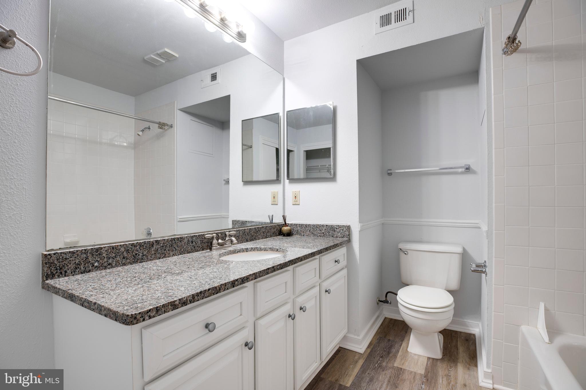 12154 Penderview Terrace, Unit 1231 Fairfax, VA 22033 - Photo 22 of 25 a bathroom with a granite countertop toilet a sink and a mirror