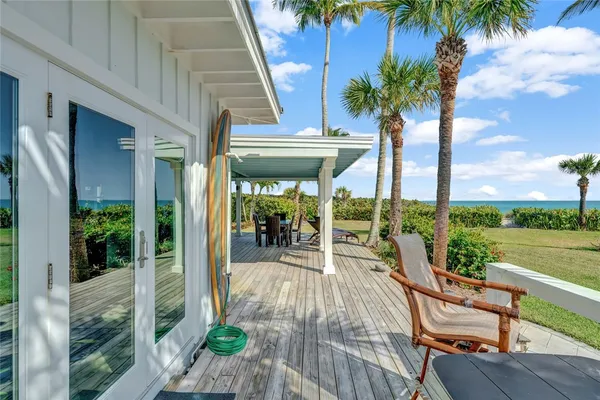 a living room with patio furniture and a floor to ceiling window next to a yard