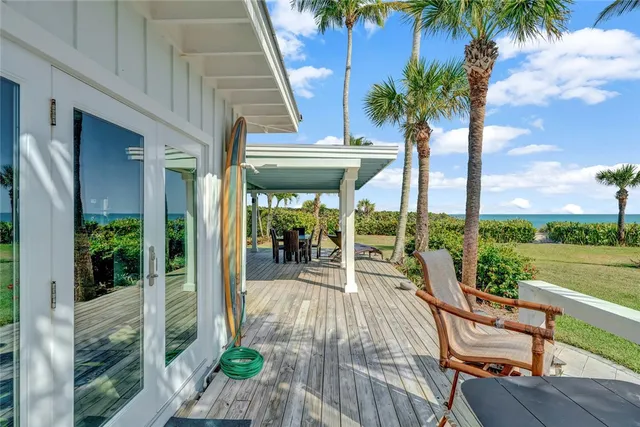 a living room with patio furniture and a floor to ceiling window next to a yard