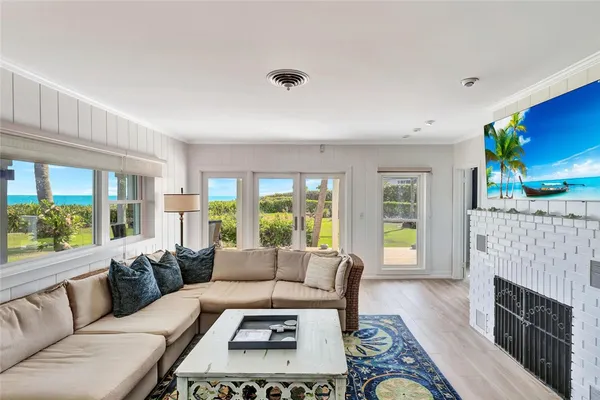 a living room with furniture floor to ceiling window and wooden floor