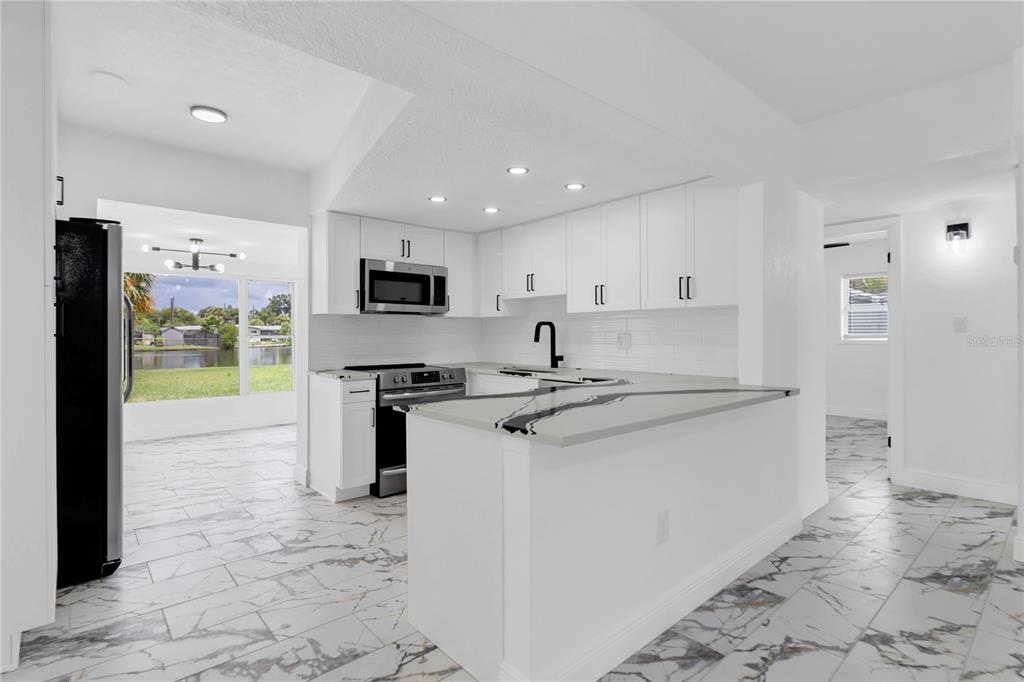 7320 Oelsner Street New Port Richey, FL 34652 - Photo 8 of 29 a kitchen with stainless steel appliances granite countertop a stove a sink and a refrigerator