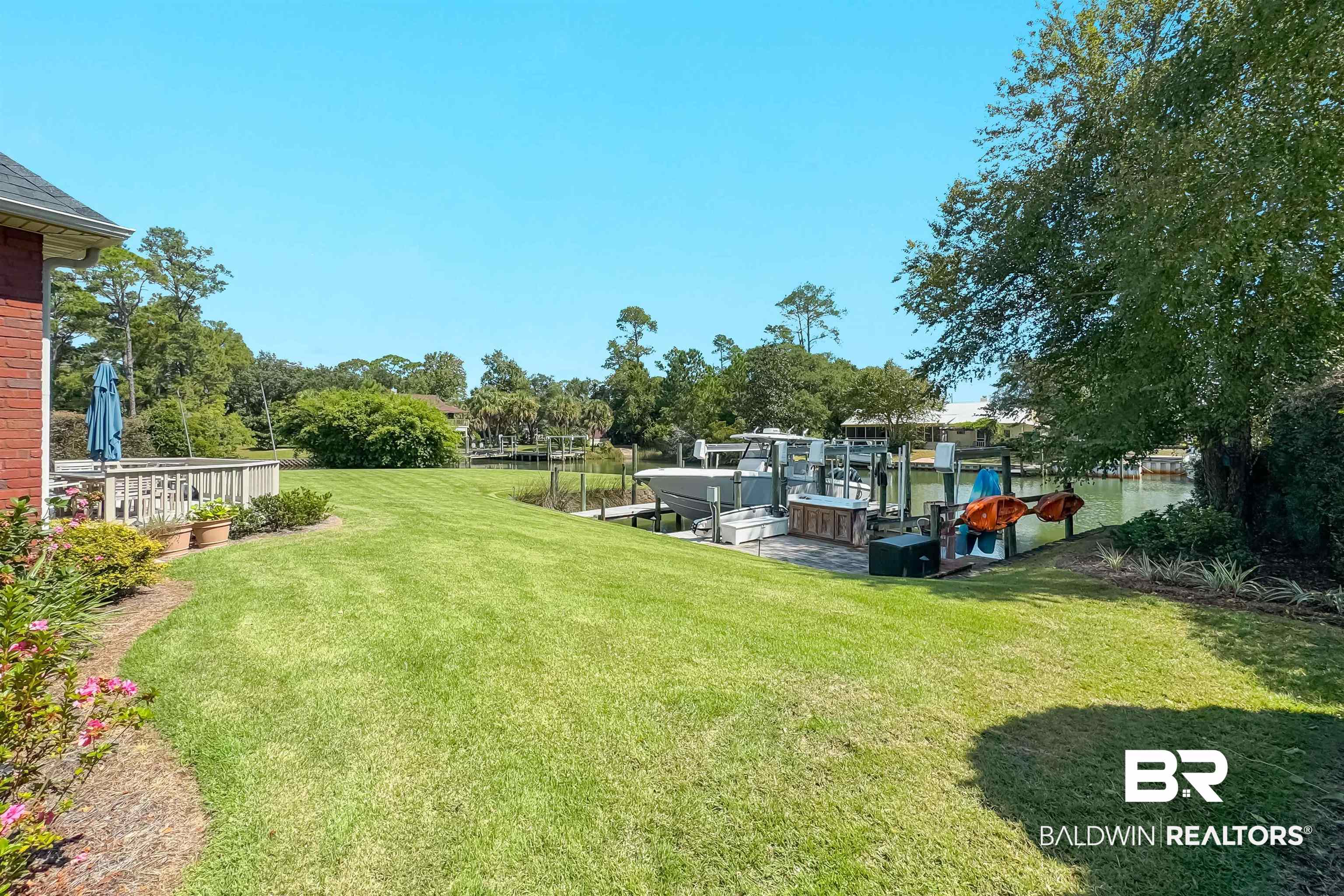 6630 East Quarry Drive Elberta, AL 36530 - Photo 48 of 63 View of green lawn featuring a dock, boat lift, and view of scattered trees