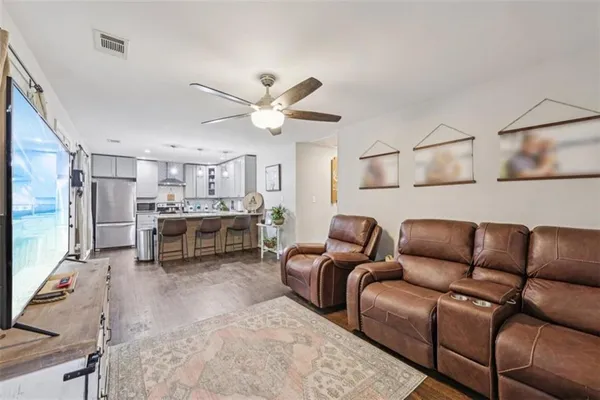 a kitchen with a refrigerator a sink dishwasher a dining table and chairs with wooden floor