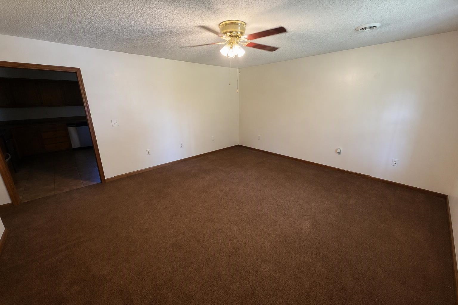 9450 Holly Grove Road Brighton, TN 38011 - Photo 5 of 10 Spacious room featuring brown carpet flooring, neutral painted walls, and a ceiling fan with integrated lighting