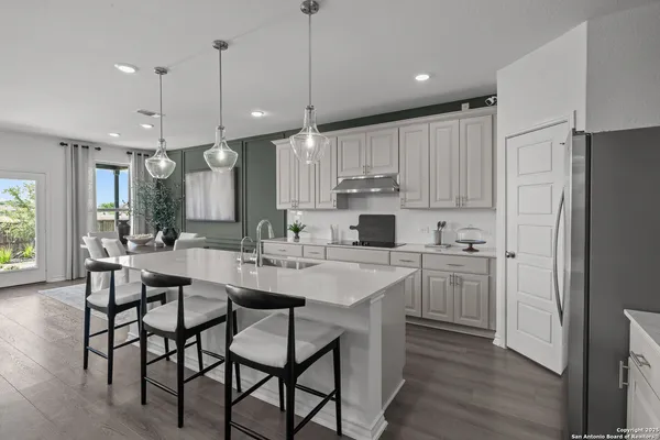 a kitchen with kitchen island granite countertop a table chairs a sink refrigerator and cabinets