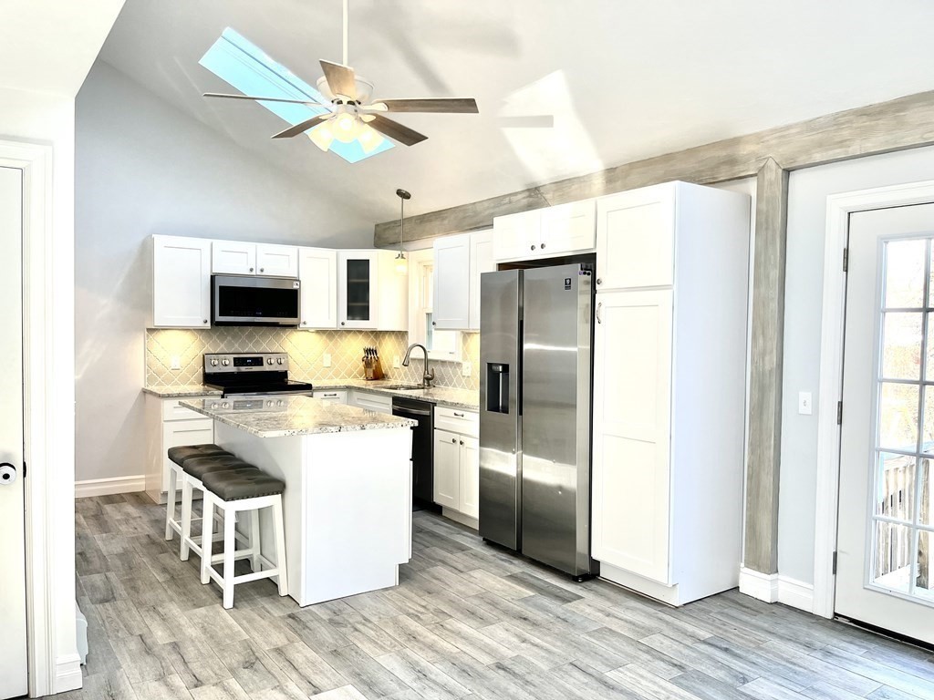 41 Lelland Road Stoughton, MA 02072 - Photo 2 of 29 a kitchen with a refrigerator a microwave a stove and white cabinets with wooden floor