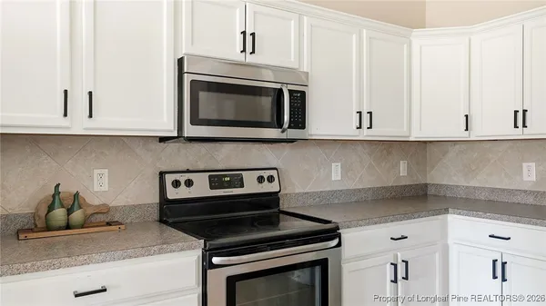 a kitchen with white cabinets and appliances