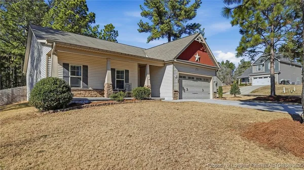 a front view of house with yard and trees in the background