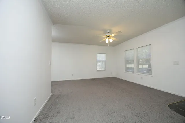 an empty room with windows and fan