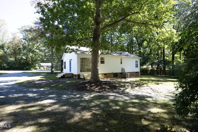 a backyard of a house with large trees and plants
