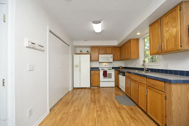 a kitchen with stainless steel appliances hardwood floor sink stove and wooden cabinets