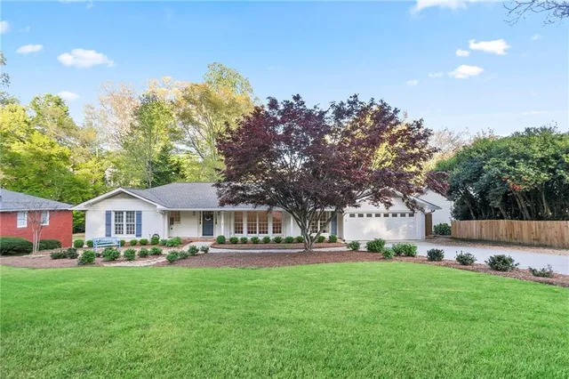 a front view of a house with a garden and trees
