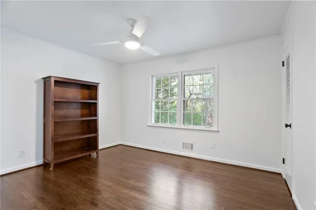 an empty room with wooden floor closet and windows