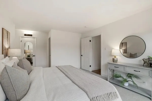 a bedroom with a bed mirror and vanity