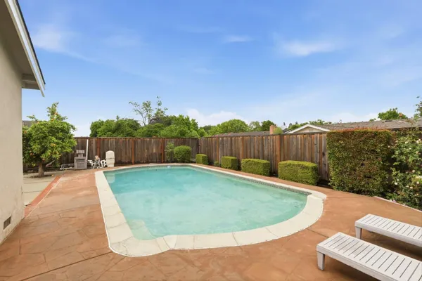 a view of a swimming pool with a patio and wooden fence