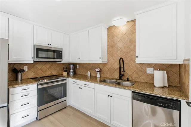 a kitchen with white cabinets and appliances