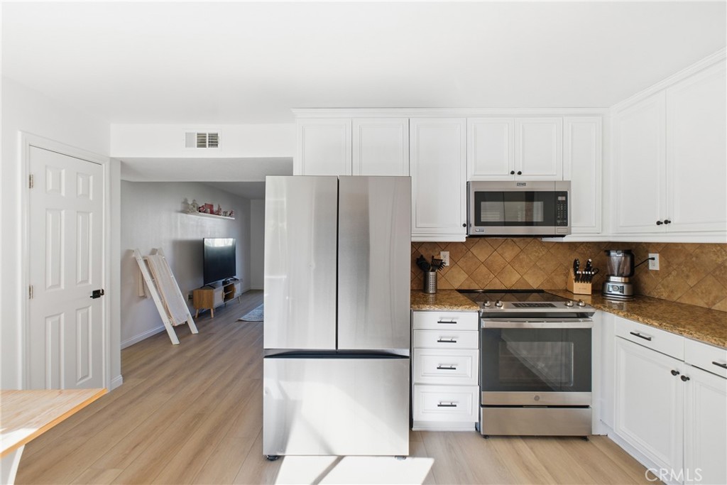 20921 Serrano Creek Road, Unit 55 Lake Forest, CA 92630 - Photo 9 of 26 a kitchen with granite countertop a refrigerator stove and white cabinets