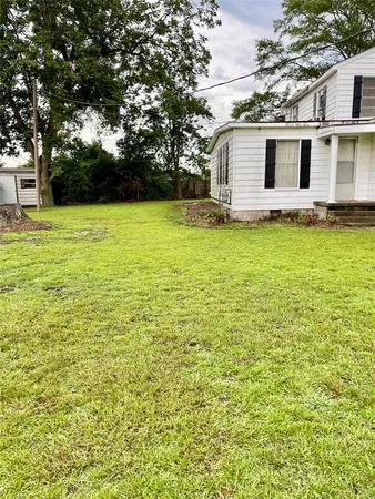 a front view of house with yard and trees in the background