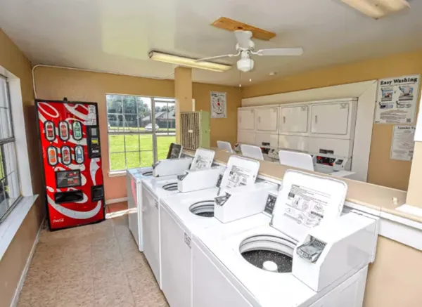 a large white kitchen with a stove a sink and dishwasher with a dining table chair