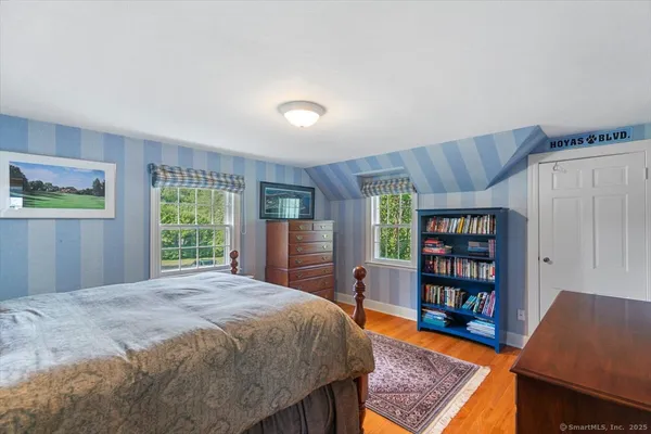 a bedroom with a bed a book shelf and a window