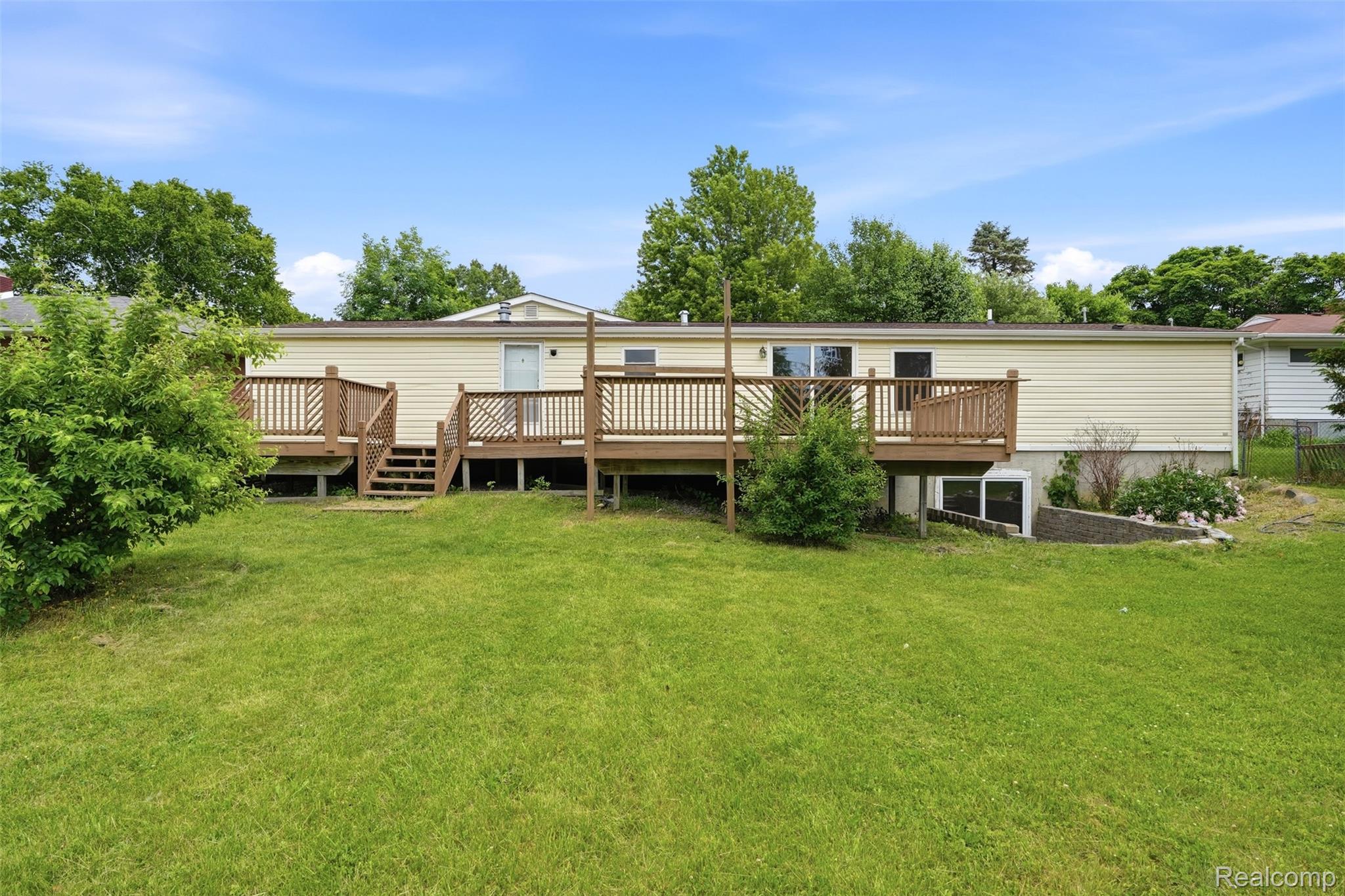 4420 Dublin Road Burton, MI 48529 - Photo 36 of 56 Expansive backyard featuring a manicured lawn, a large wood-finish deck with railings, and dual sliding glass doors offering access to the interior