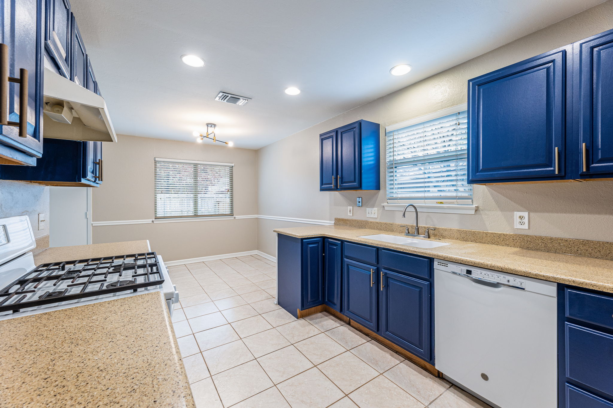 12914 Pegasus Street Austin, TX 78727 - Photo 11 of 30 Kitchen with blue cabinets, dishwasher, light tile patterned flooring, plenty of natural light, and recessed lighting