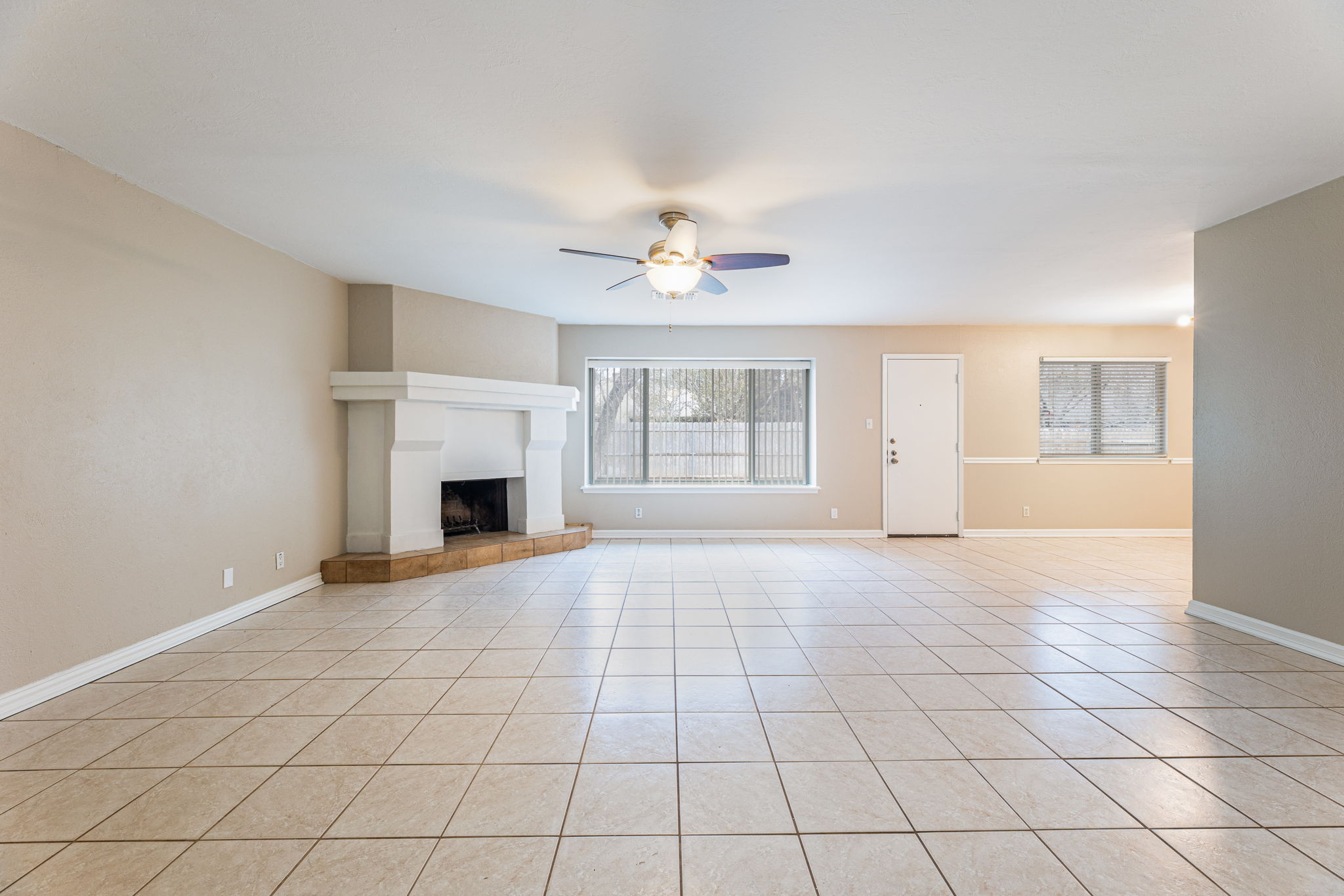 12914 Pegasus Street Austin, TX 78727 - Photo 4 of 30 Unfurnished living room with a tiled fireplace, ceiling fan, and light tile patterned flooring