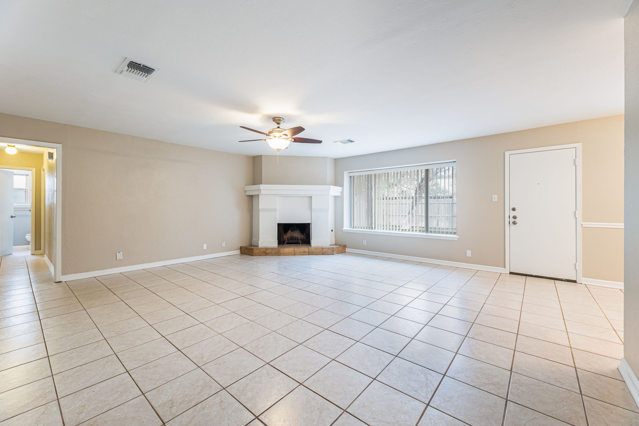 12914 Pegasus Street Austin, TX 78727 - Photo 6 of 30 Unfurnished living room featuring a ceiling fan, a fireplace with raised hearth, and light tile patterned flooring